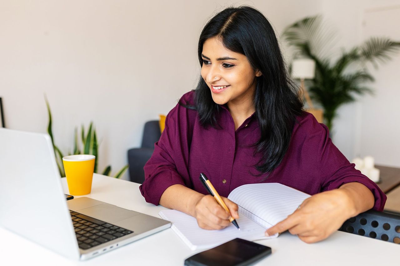 young girl with dark hair budgeting on computer and using paper